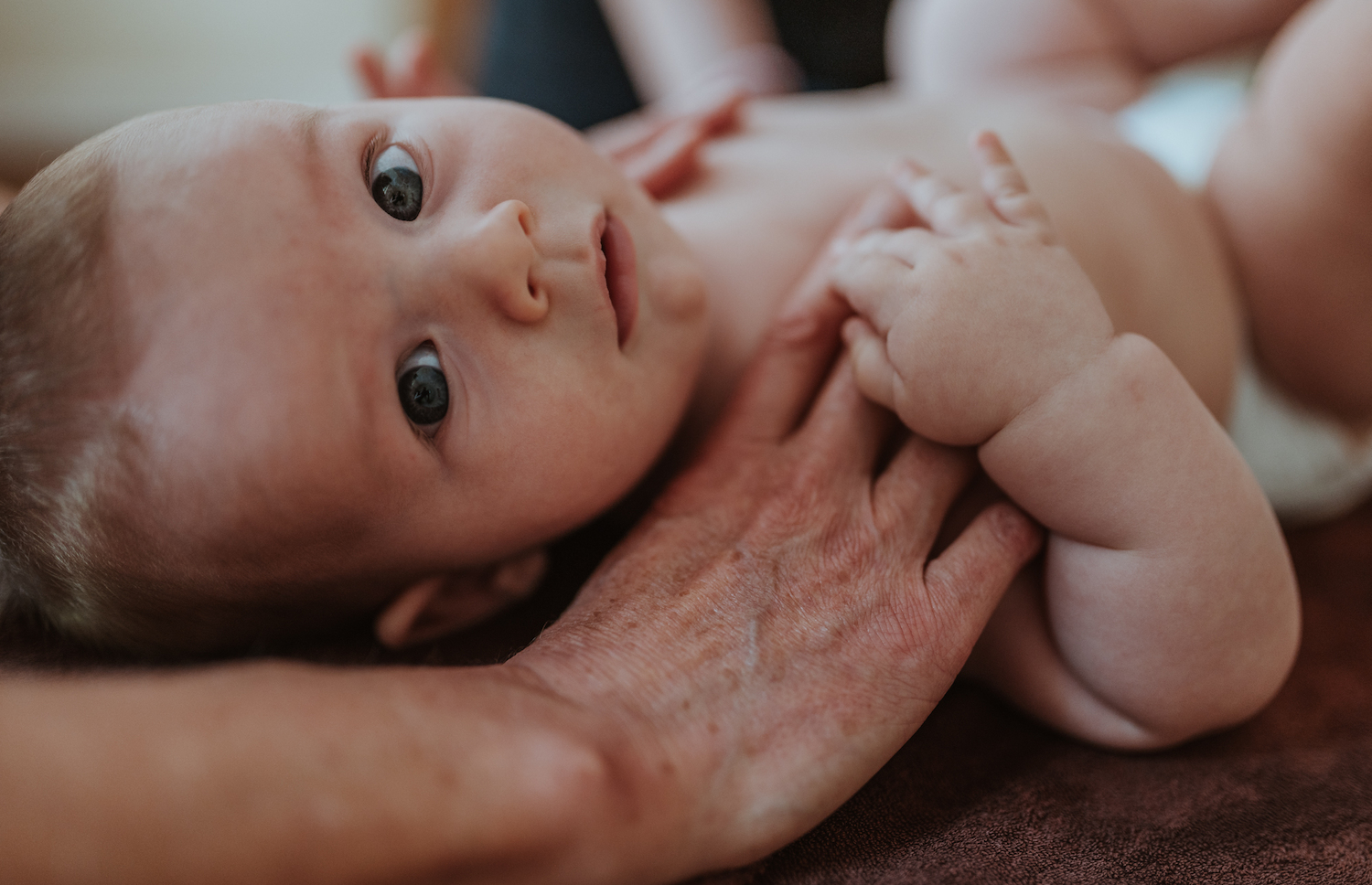Osteopathie Praxis Hamburg Altona Ottensen Osteopathin Inga Gaertner in Altona behandelt ein Baby, das Baby schaut entspannt in die Kamera